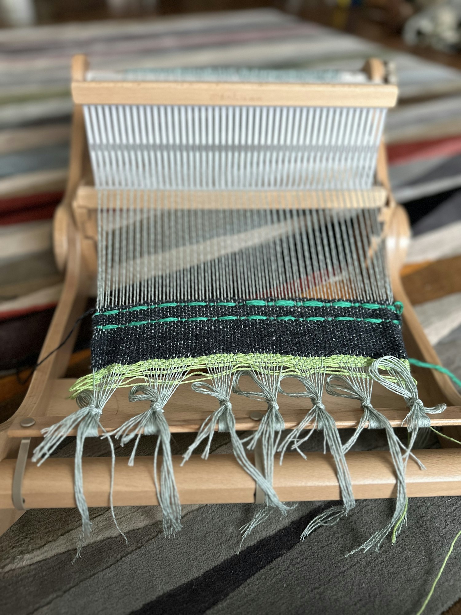 Photo of my current weaving project in dark gray and bright green stripes